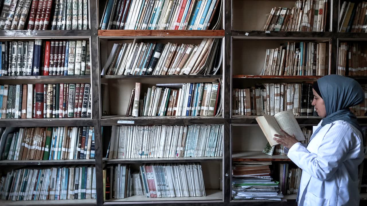 the library stacks, a conservator reaching into them.