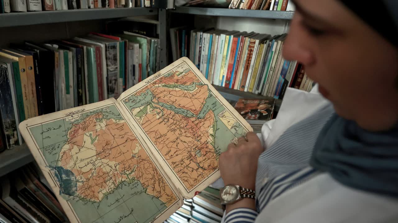 an open hand-coloured atlas held up to the light.
